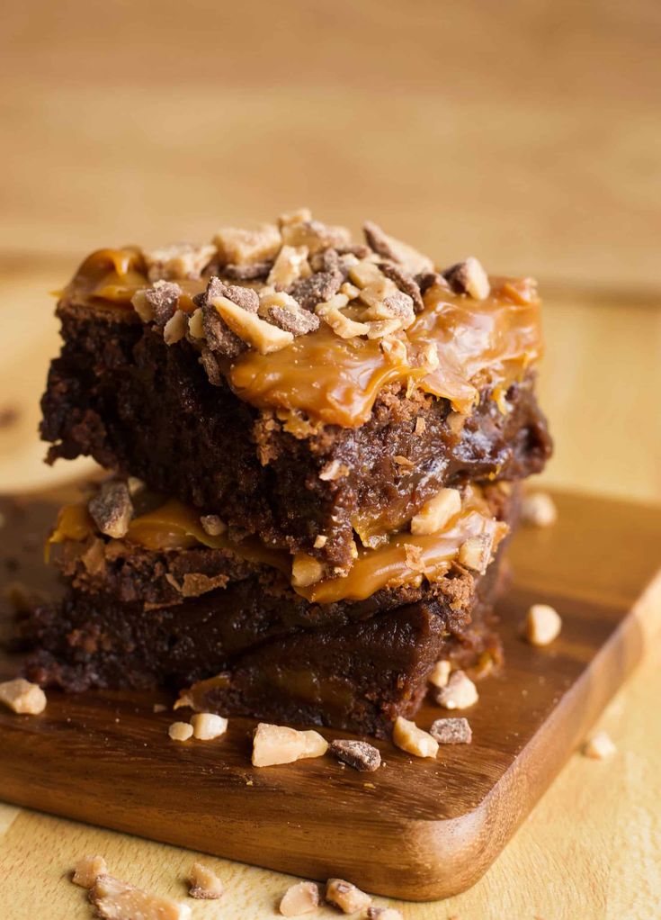 two brownies stacked on top of each other with caramel drizzle and nuts