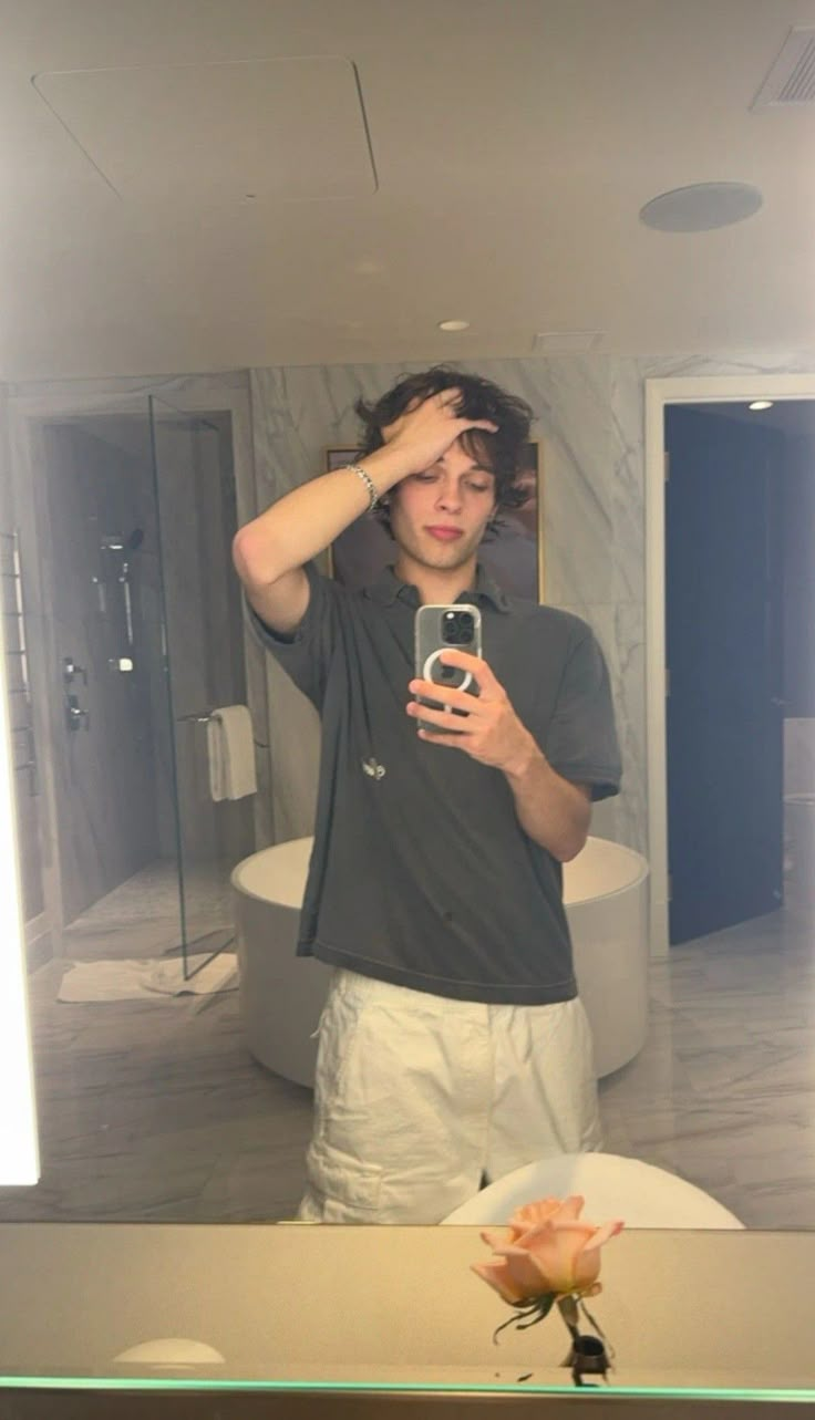 a man taking a selfie in front of a bathroom mirror with his cell phone