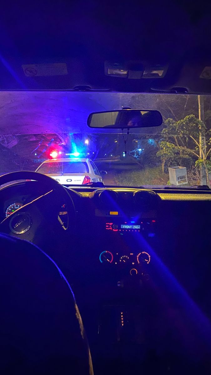 a police car with its lights on at night in the dark, and it's dashboard