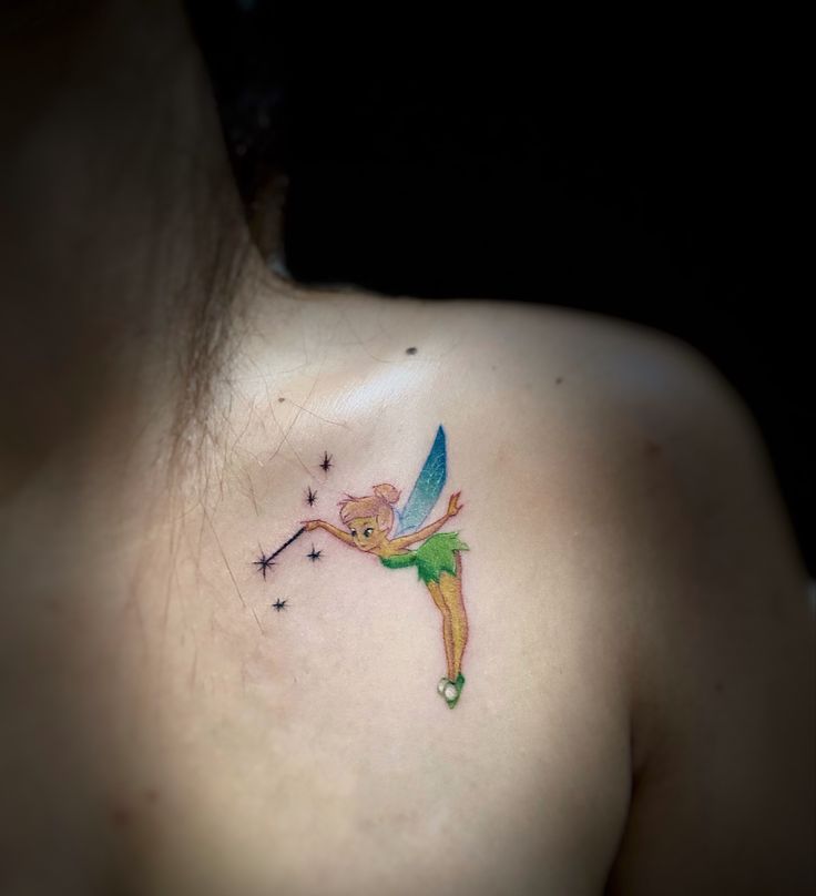 a woman's chest with a small tattoo of a tinkerbell on it