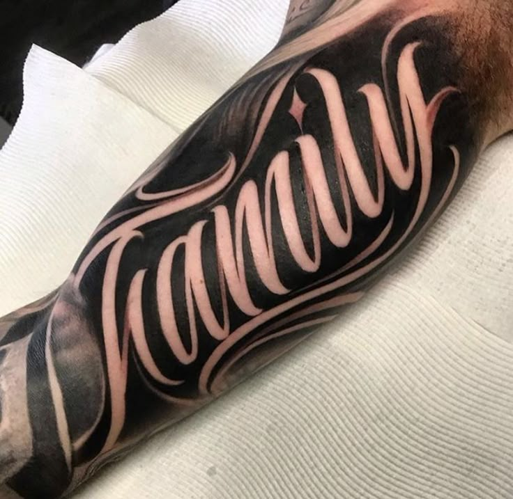 a man with a black and white tattoo on his arm has the word genius written in cursive writing