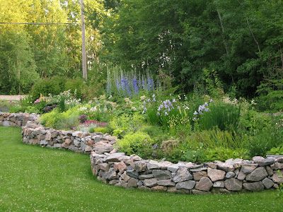 a stone wall in the middle of a garden