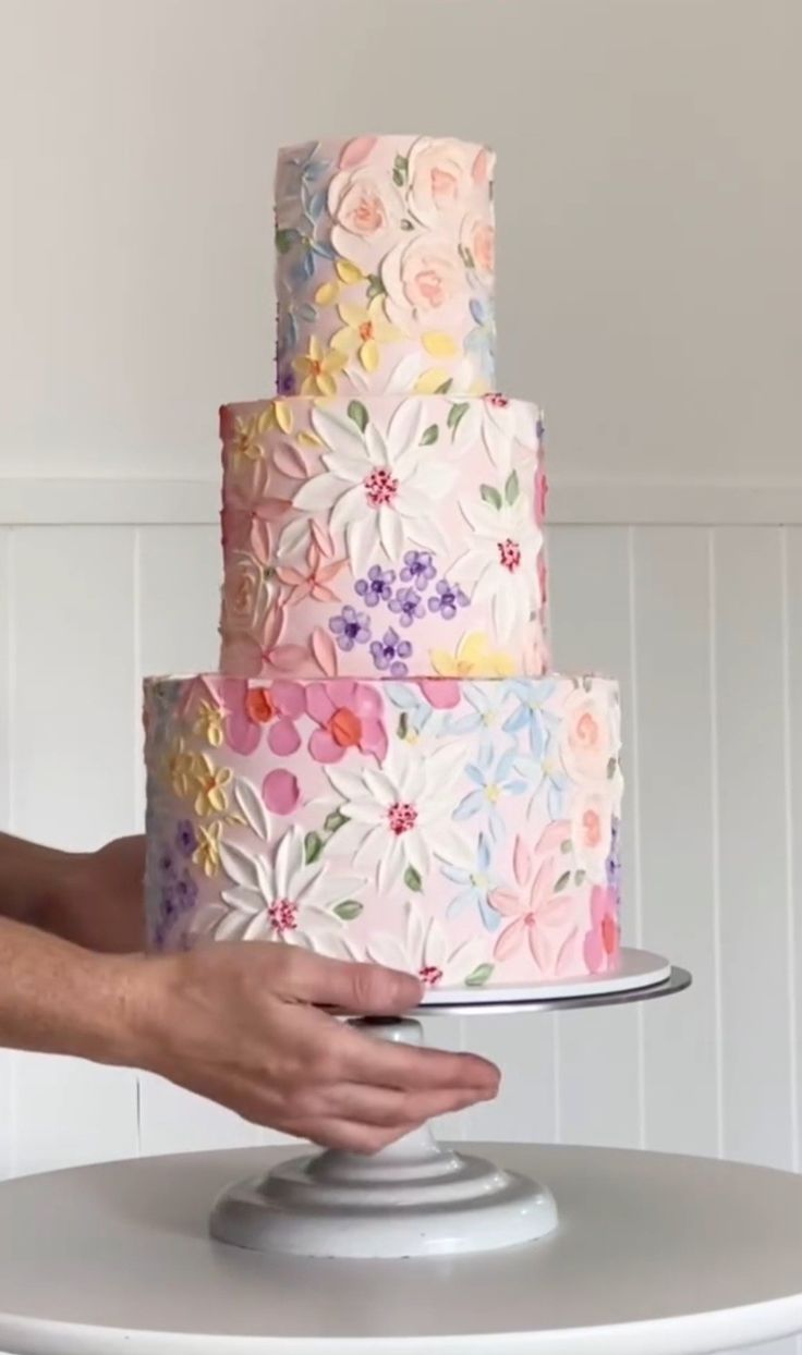 a person holding a multi layer cake on top of a table