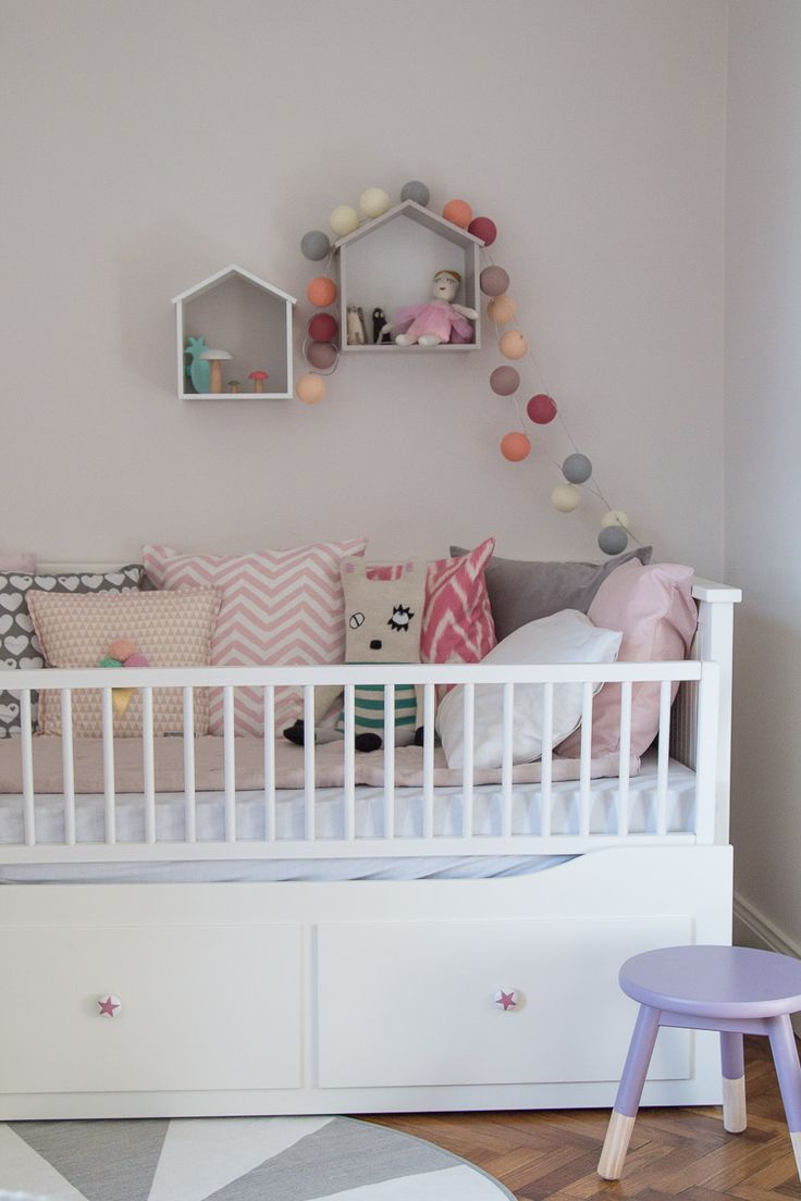 a baby's room with a white crib and lots of pillows