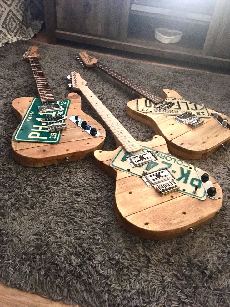 three wooden guitars are laying on the carpet