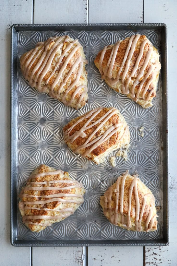 six scones with icing sitting on a metal baking sheet, ready to be baked