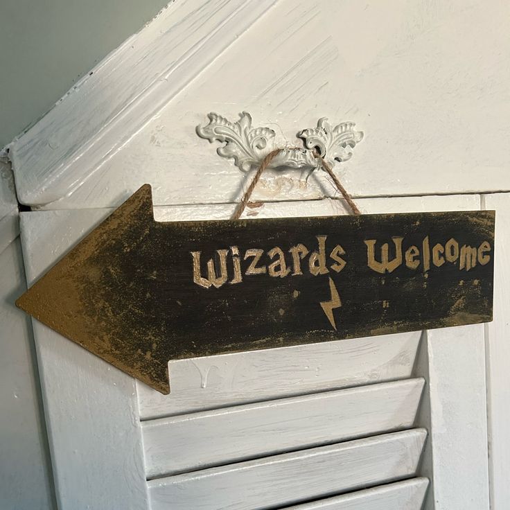 a wooden sign hanging from the side of a white door that says wizard's welcome