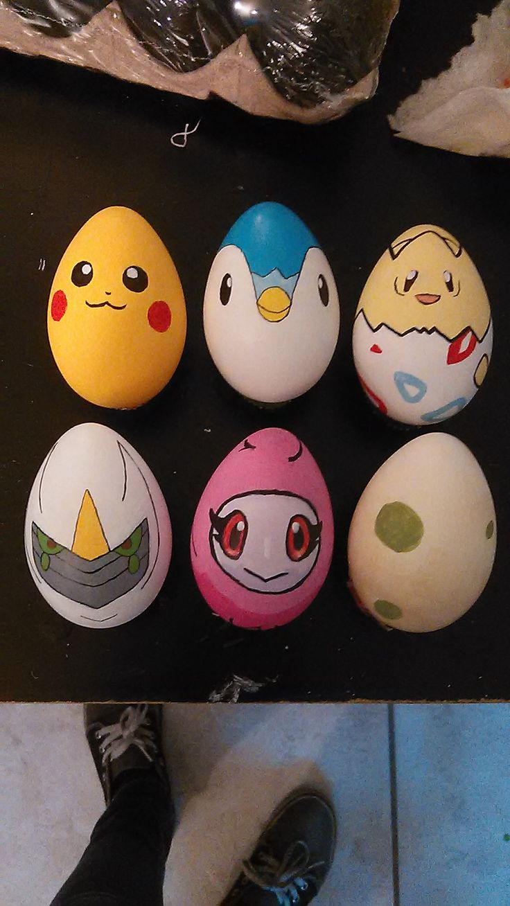 an assortment of painted eggs sitting on top of a black table next to a person's feet