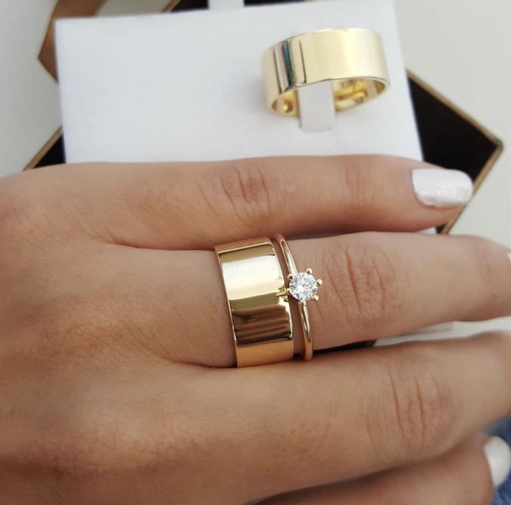 a woman's hand with two gold rings and one diamond ring on her finger