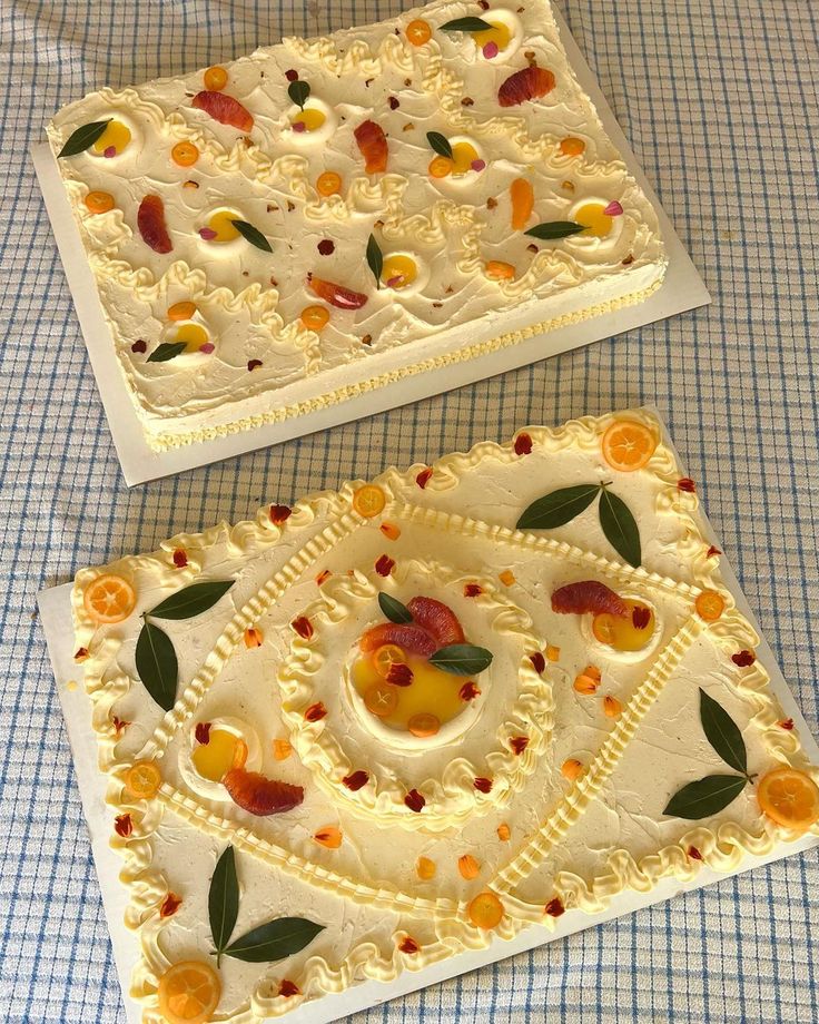 two cakes with fruit on them sitting on a table