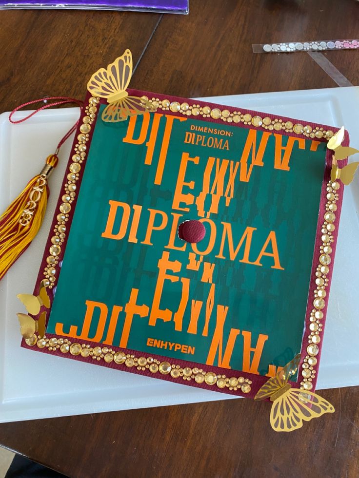 a green and gold graduation cap on top of a white plate with tassels