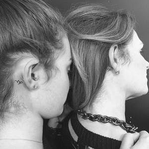 two women with tattoos on their neck looking into each other's eyes