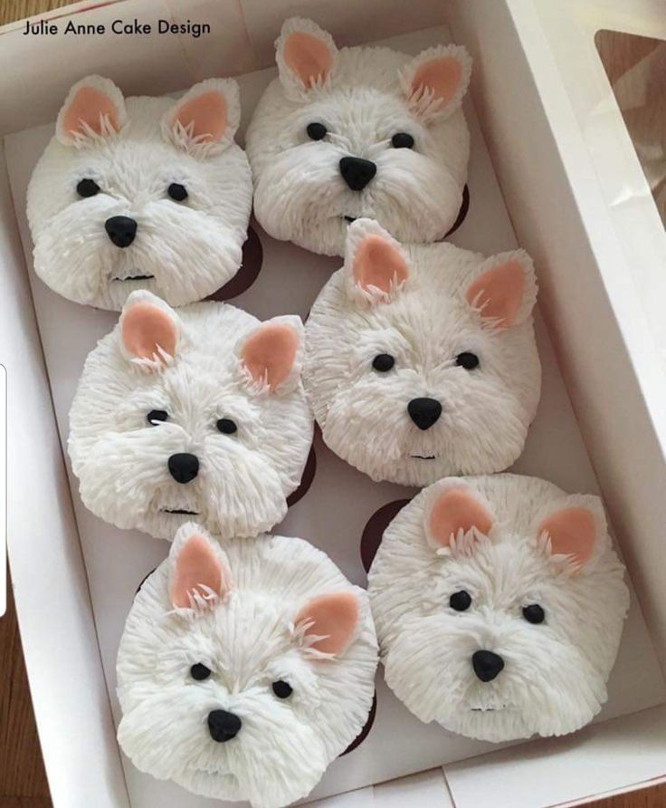 cupcakes with white frosting and pink ears are in a box on the table