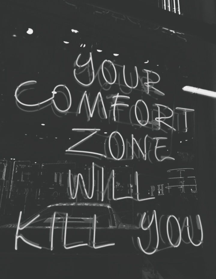 a black and white photo with writing on the side of a building that says your comfort zone will kill you