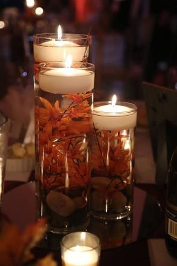 candles are lit in glass vases on a table