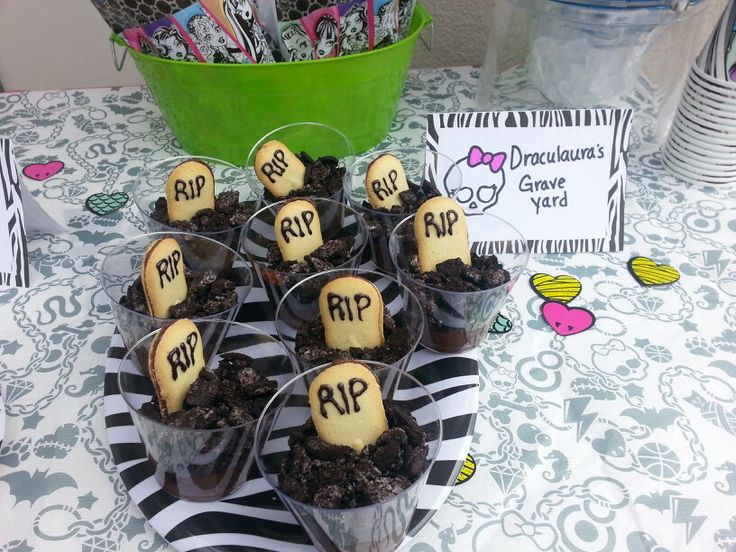 some cupcakes are sitting in plastic cups on top of a table with candy