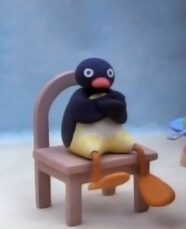 an animated penguin sitting on a wooden chair