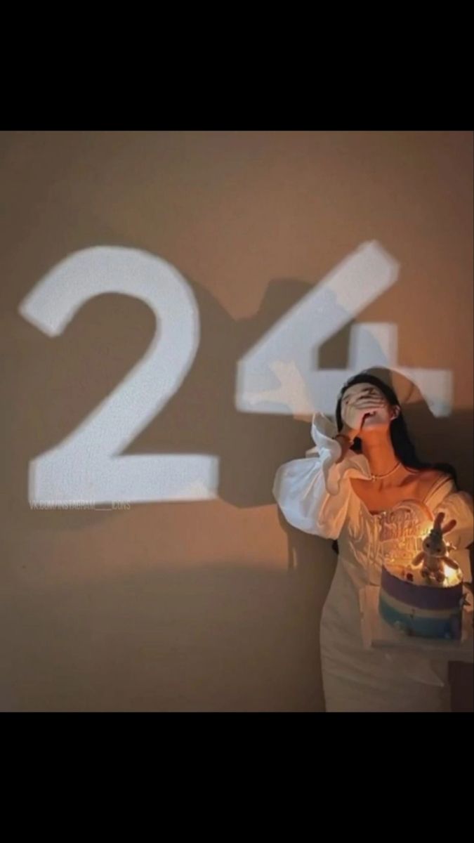 a woman standing in front of a wall with the number twenty four projected on it