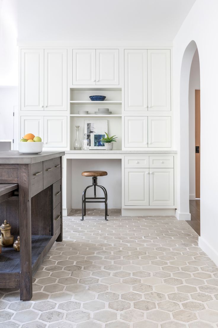 a kitchen with white cabinets and an island in the middle is seen from across the room