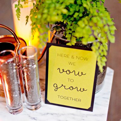 there is a plant on the table with two glasses and a sign that says here & now we love to grow together