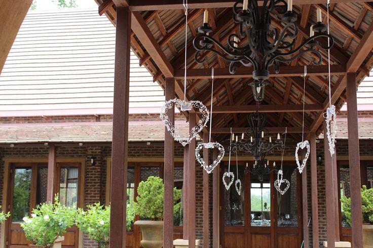 a chandelier hanging from the ceiling in front of a wooden building with potted plants