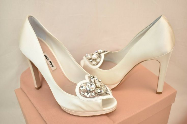 BIANCO/ WHITE SATIN JEWELED CRYSTALS PLATFORM PEEP TOE WEDDING DRESS PUMPS   By MIU MIU PRADA   MADE IN ITALY   100% AUTHENTIC,GUARANTEED!!!   Add some height to your step with a fabulous pair of Satin Dress /Wedding  platforms pumps Miu Miu Prada!   Color: Bianco/white Satin upper Tapered  peep toe Leather Trim Jeweled Crystal Heart Shape Detail  vamp 4 3/4" covered  heel 1/2" front platform Leather lined "MIU MIU" Stamped logo Leather sole Size 37.5-print on the shoes and box   Wear them to ad Feminine Fitted White Wedding Shoes, Satin Dress Wedding, Wedding Platform, Boda Ideas, Wedding Pumps, Wedding Shoes Heels, Pump Dress, Satin Dress, Platform Pumps