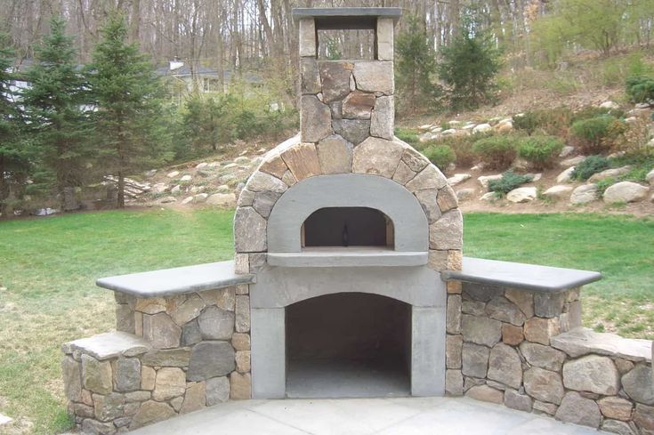 an outdoor stone pizza oven in the middle of a yard