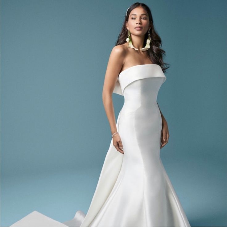 a woman in a white wedding dress posing for a photo with her hands on her hips