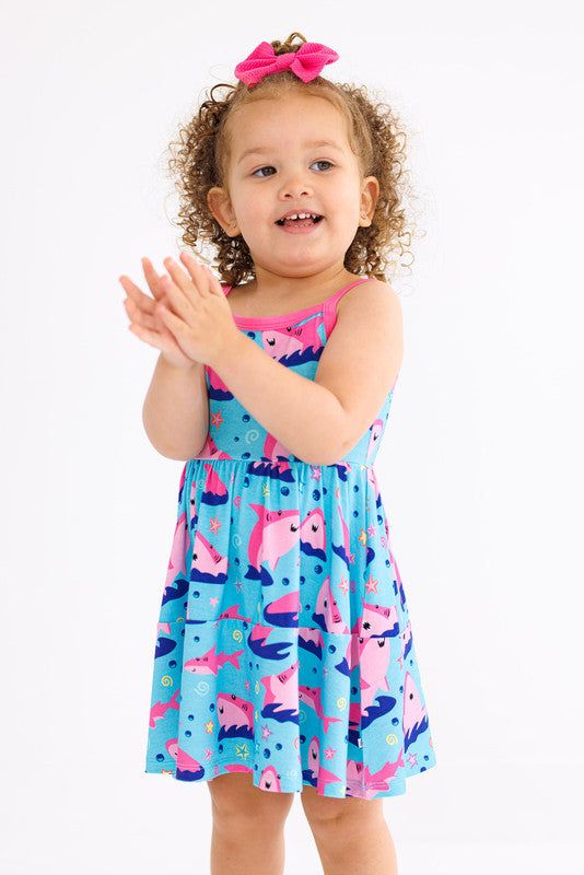 Crafted from luxurious bamboo viscose and spandex fabric, this birdie dress is designed to be comfortable and lightweight, keeping your little one cool and confident all day long. Its playful design adds a fun twist to any wardrobe. It's the perfect blend of comfort, style, and durability. About Me: Soft and luxurious Made from bamboo viscose not treated with any harsh chemicals Size ranges from 2T to 7-8 years Material: 95% Viscose from Bamboo, 5% Spandex Machine wash / Tumble dry low, lay flat, or hang to dry Do not bleach / Use color catcher sheets to prevent color transfer Style: Dresses for girls Product: Birdie Bean Sleeveless Dress - Gwen (Baby Sharks) Casual Summer Twirl Dress For Playwear, Playful Summer Beach Twirl Dress, Playful Sleeveless Dress For Spring Vacation, Playful Cotton Twirl Dress For Beach, Cotton Stretch Dress For Playwear, Stretch Cotton Dress For Playwear, Playful Spring Sundress For Playwear, Playful Twirl Dress For Summer Playdate, Playful Sleeveless Twirl Dress For Playwear