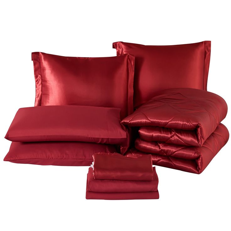 a bed with red sheets and pillows on top of each other in front of a white background