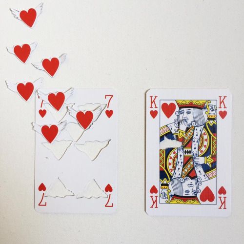 playing cards with hearts on them sitting next to each other in front of a white wall