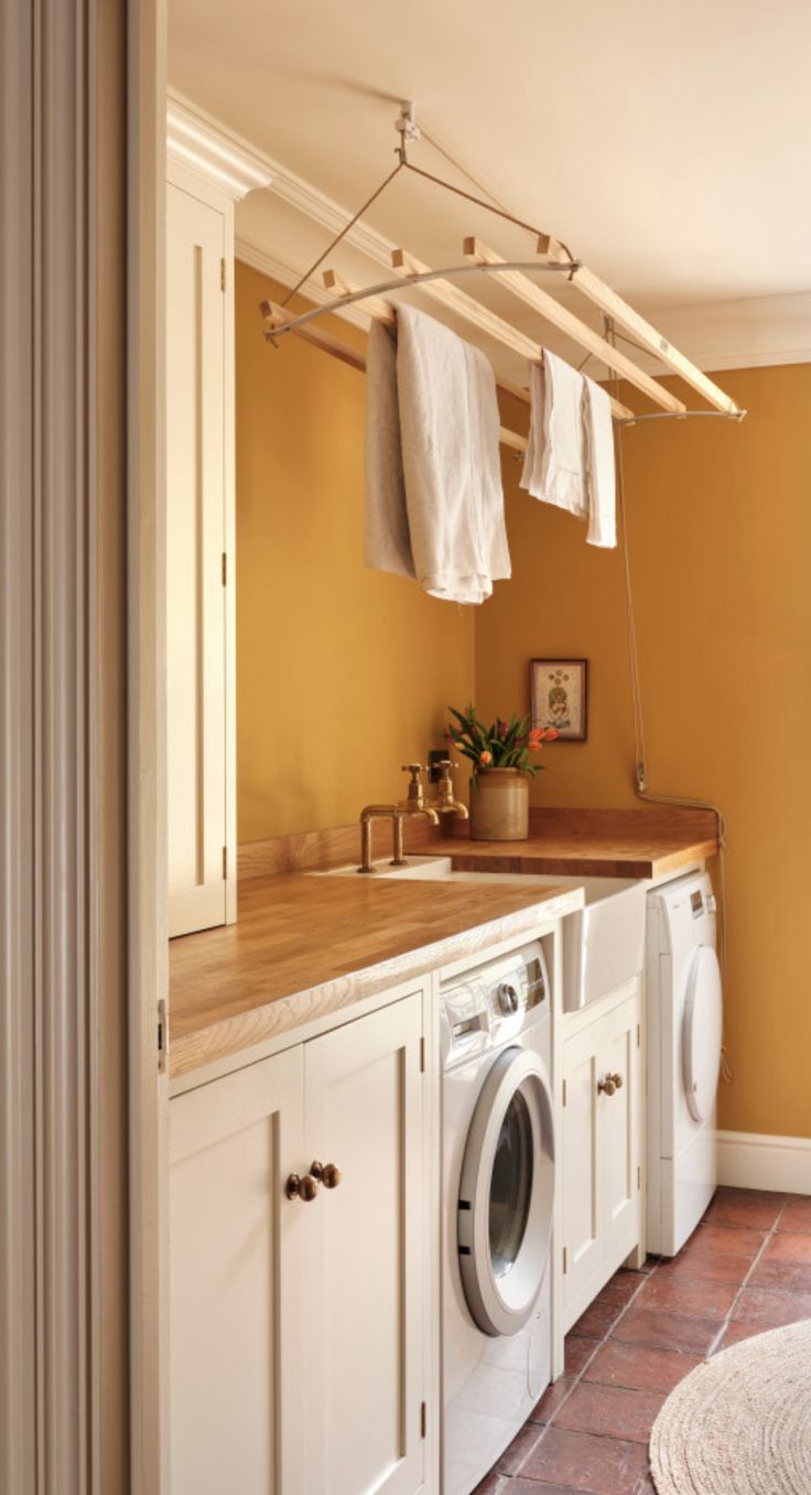 a washer and dryer in a room with yellow walls, tile flooring and white cabinets