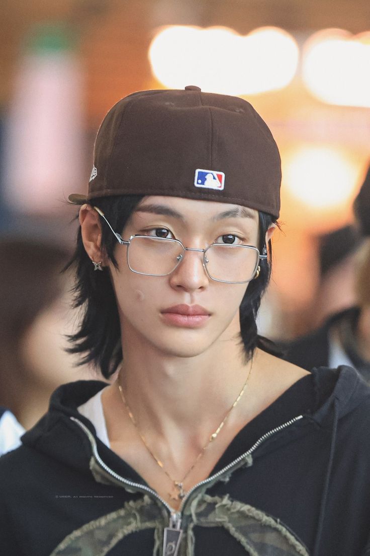 a young man wearing glasses and a baseball cap