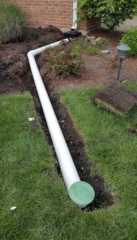 a white pipe laying in the grass next to a house