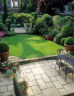 an outdoor patio with potted plants and tables in the foreground, surrounded by greenery