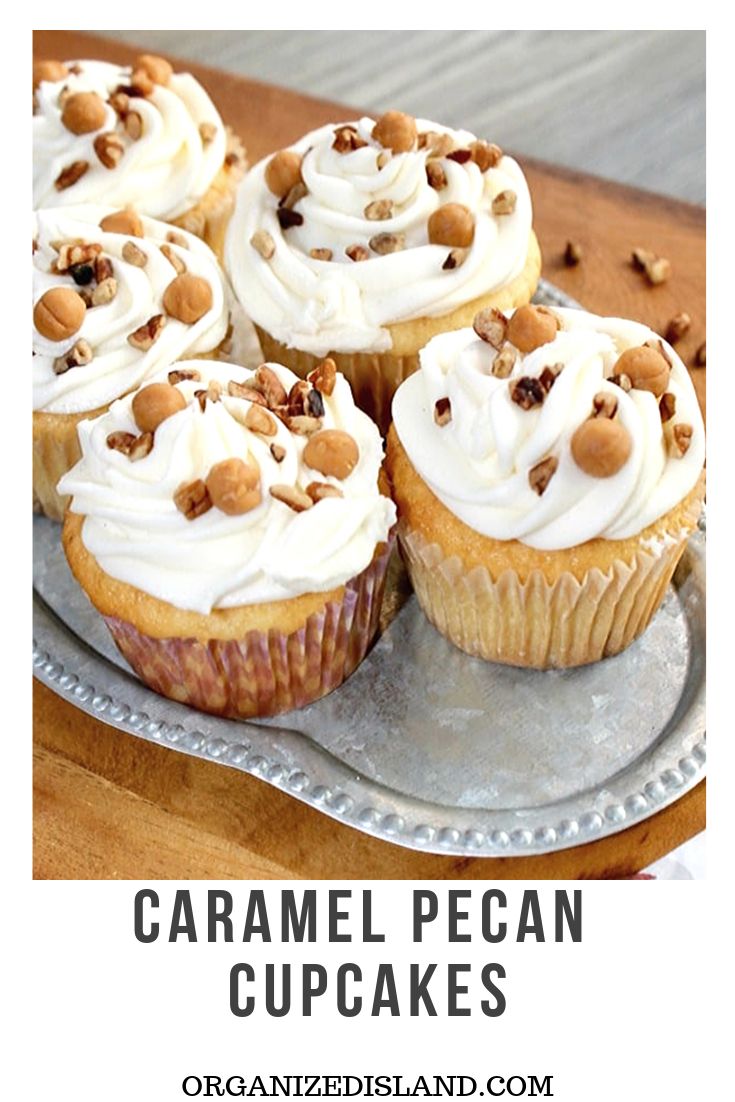 several cupcakes with white frosting and nuts on a silver plate next to a napkin