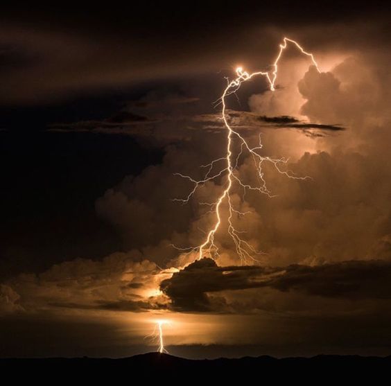 a lightning bolt is seen in the sky above some dark clouds at night with bright lightening