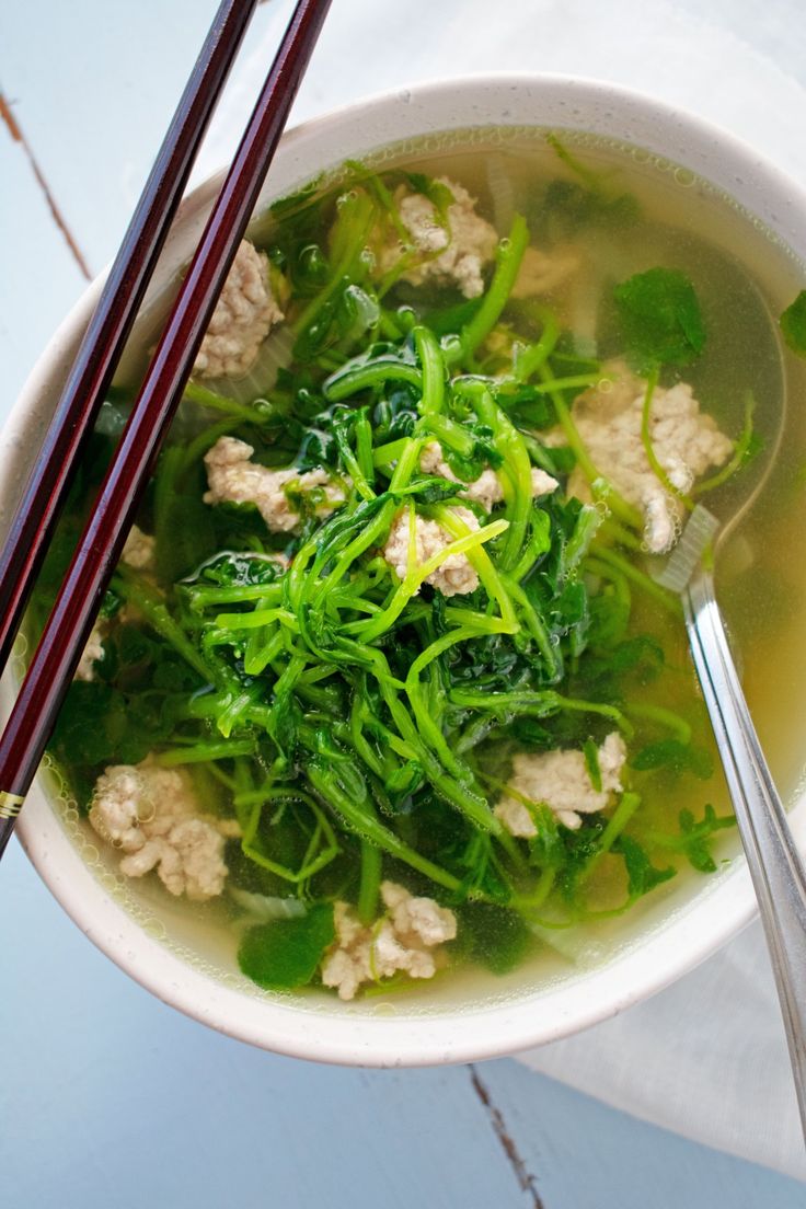 a bowl filled with soup and chopsticks sitting on top of a white table