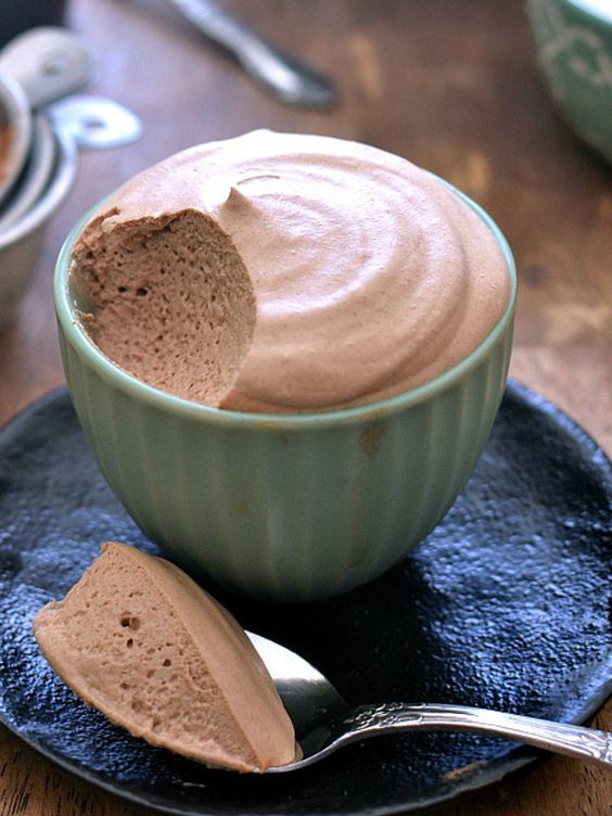 a bowl of chocolate pudding on a plate with a spoon