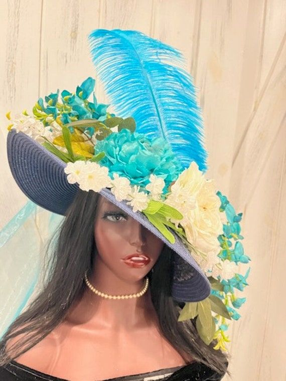 Ready to ship today from Tennessee, USA! I ship quickly and package safely in boxes. Follow this link for more beautiful hat choices from Equine Elan Hats at https://www.etsy.com/shop/Equineelan This hat has all the features to make it a favorite at any event. I added a turquoise ostrich feather to lift this hat into derby level. The wide brim navy blue hat is totally surrounded with white and turquoise flowers. A big turquoise crinoline bow accents the rear of the hat. Ostrich feathers have bee Blue Feathered Wedding Costume Hat, Blue Adjustable Costume Hats For Carnival, Adjustable Blue Costume Hats For Carnival, Blue Wedding Costume Hat With Feathers, Whimsical Blue Wide Brim Hat, Whimsical Blue Wide-brim Hat, Blue Mini Hats For Royal Ascot Garden Party, Blue Costume Hats And Headpieces For Carnival, Blue Feathered Costume Hats And Headpieces For Spring