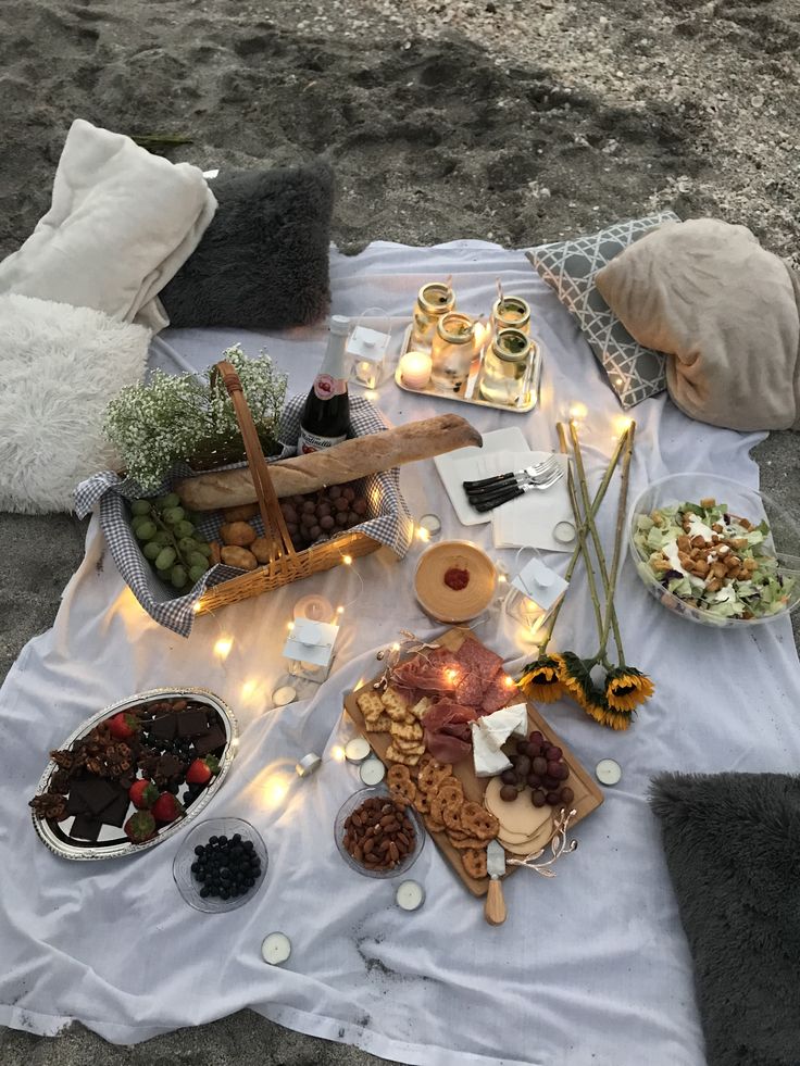 a table topped with lots of food sitting on top of a white cloth covered ground