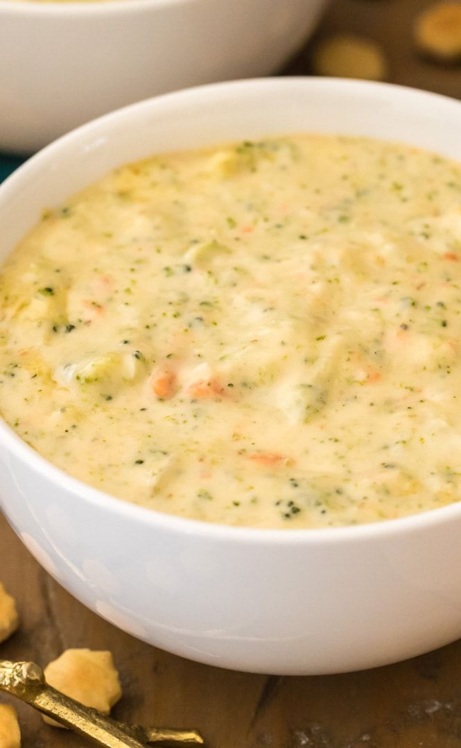 two white bowls filled with soup sitting on top of a wooden table next to crackers