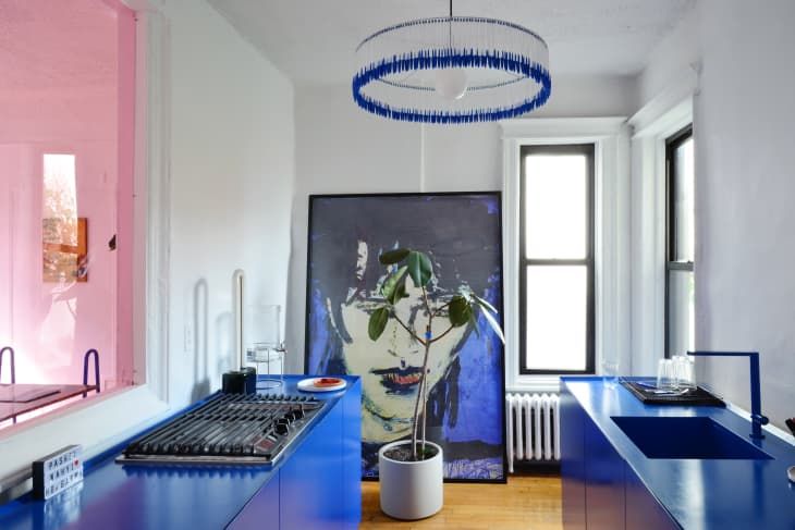 a kitchen with blue counter tops and white walls in the background is a painting on the wall