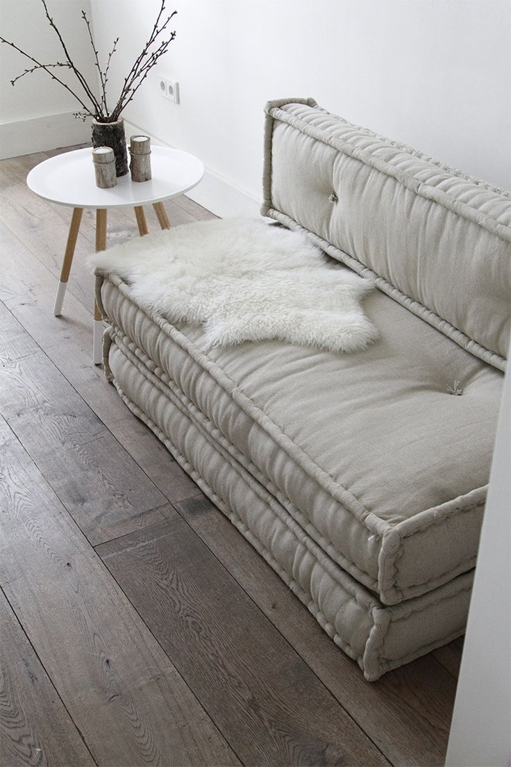 a white couch sitting on top of a wooden floor next to a vase with flowers