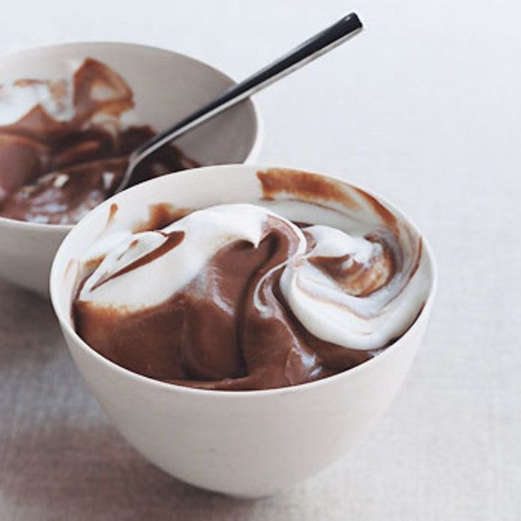 two white bowls filled with chocolate and marshmallows on top of a table