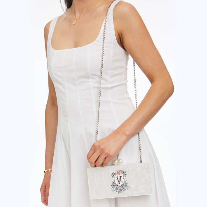 This one-of-a-kind floral crest clutch is perfect for a garden party, bridal shower or wedding. Featuring a stunning white marble design and a mirror inside. A removable chain turns this clutch into a crossbody to complement any gown or sundress. The ornate floral crest can be customized with your initials or family name for a clutch that is truly unique.    8"w x 2"d x 4"h  Acrylic.  Strap: 43"l  Wipe with a damp cloth.  Imported.  Monogramming is vinyl decal. Elegant Summer Wedding Clutch, Summer Wedding Clutch Evening Bag, Elegant Rectangular Spring Evening Bag, Elegant Rectangular Evening Bag For Spring, Elegant Summer Clutch, Elegant Evening Bag For Summer, Elegant Summer Evening Bag, Rectangular Evening Bag For Spring Events, Spring Event Rectangular Evening Bag