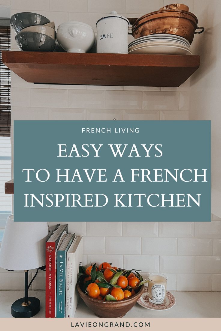 Kitchen counter with bowl of oranges, 3 French cookbooks and a candle. 2 dark wood shelves with plants and silverware. French Minimalist Kitchen, Small French Kitchen Ideas, Small Parisian Apartment Kitchen, Parisian Small Kitchen, Classic French Kitchen Design, Minimal French Decor, French Chic Kitchen, French Country Life, French Kitchen Style