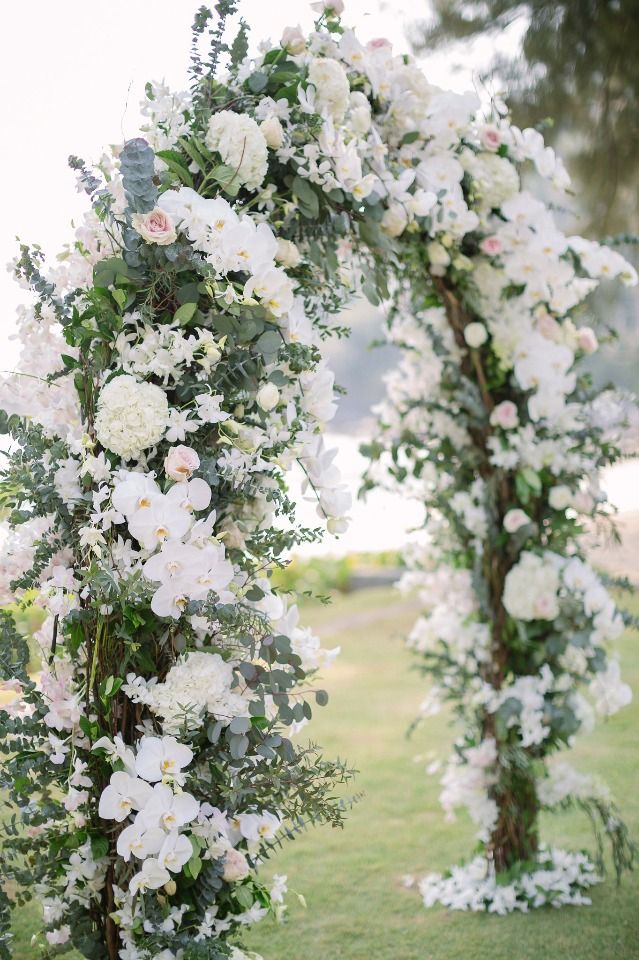 an outdoor wedding ceremony with white flowers and greenery on the side of the aisle