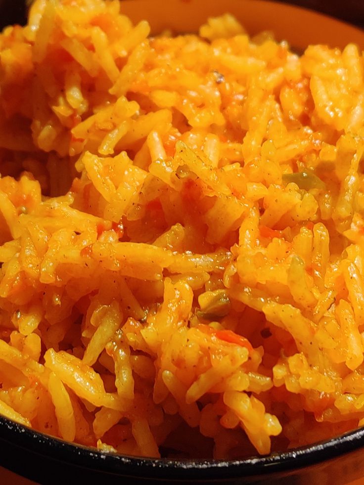 a bowl filled with rice and carrots on top of a wooden table