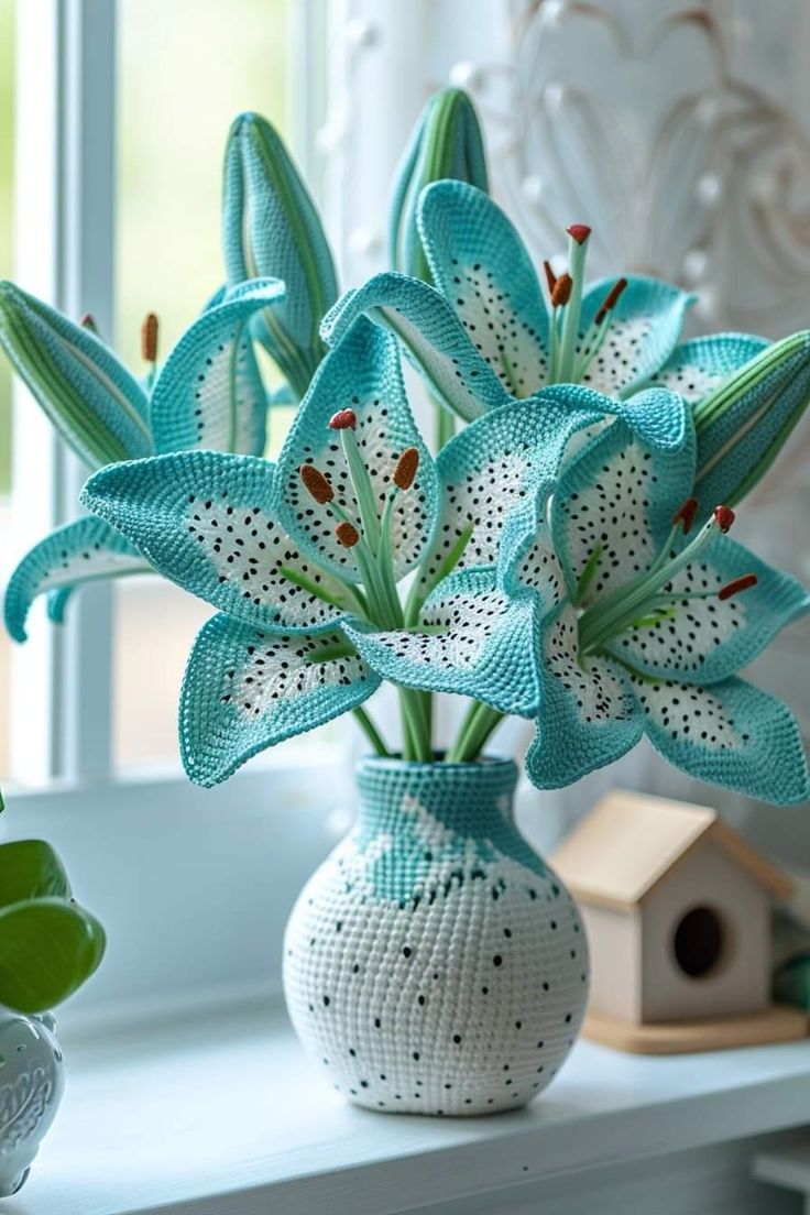 a vase with flowers in it sitting on a window sill next to a birdhouse